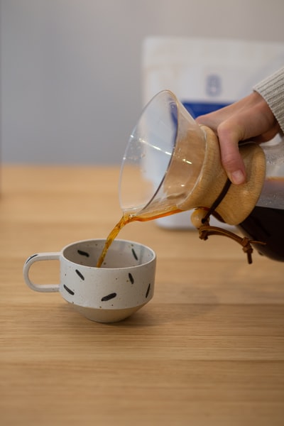 拿着白色和棕色陶瓷杯的人
